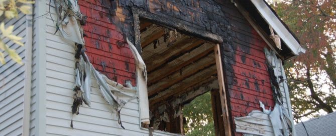 Fire damaged home with melted siding and broken glass