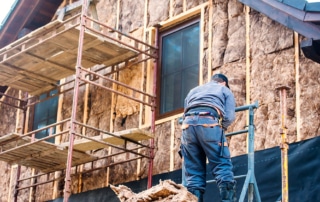 Construction worker on scaffolding repairing the exterior of a home