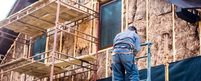 Construction worker on scaffolding repairing the exterior of a home