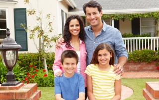 Family of four standing in the front yard of their home