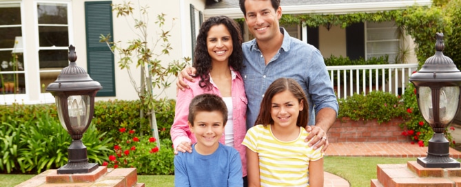 Family of four standing in the front yard of their home