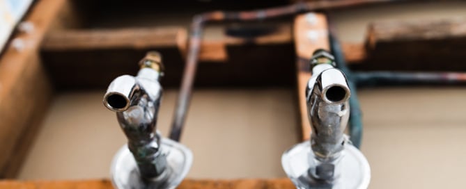Two faucets on a wall with drywall torn out for repairs